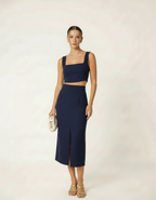 Modelo posando com conjunto cropped e saia midi azul marinho com bolsa bege - Amarine