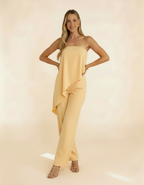 Modelo posando com macacão tomara-que-caia amarelo manteiga, mãos na cintura - Amarine