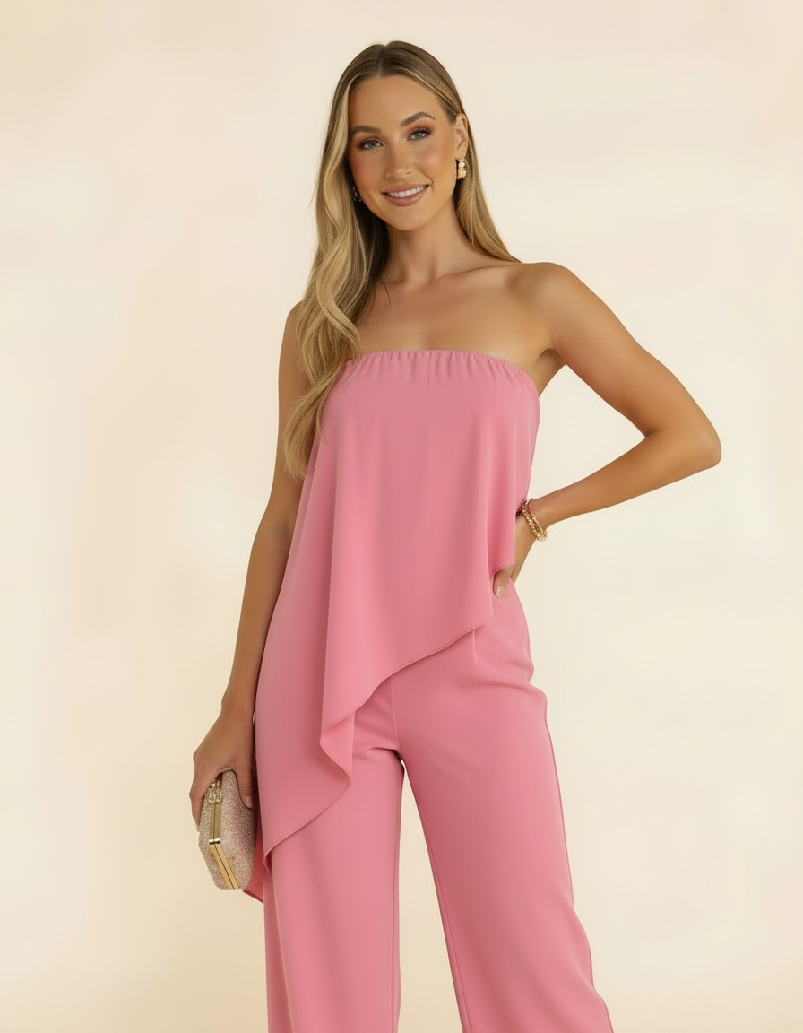 Modelo sorrindo com macacão tomara-que-caia rosa, zoom in, segurando bolsa dourada - Amarine