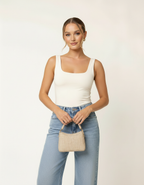 Modelo posando com regata off-white gola quadrada, calça jeans e bolsa de palha bege - Amarine
