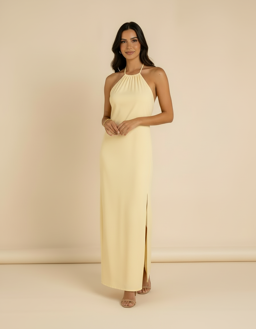 Modelo com mãos juntas usando vestido longo amarelo manteiga com gola halter e fenda lateral - Amarine