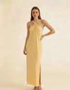 Modelo posando com vestido longo amarelo manteiga de gola halter, mão na cintura com fenda - Amarine