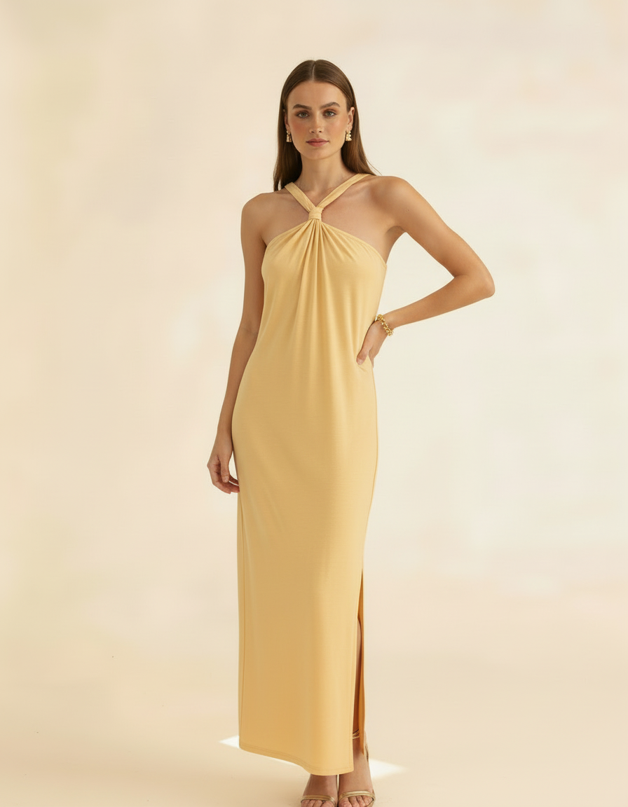 Modelo posando com vestido longo amarelo manteiga de gola halter, mão na cintura com fenda - Amarine