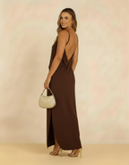 Modelo de costas com vestido longo marrom chocolate de decote profundo nas costas e bolsa dourada - Amarine