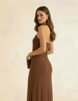 Modelo posando lateralmente com vestido longo marrom chocolate, segurando bolsa - Amarine