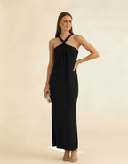 Modelo posando com vestido longo preto de gola halter, segurando bolsa dourada - Amarine
