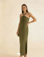 Modelo posando com vestido longo verde oliva de gola halter com fenda lateral, segurando bolsa - Amarine