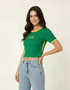 Mulher posando com mão na cintura usando blusa cropped verde estilo Brasil e calça jeans clara