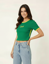Mulher posando com mão na cintura usando blusa cropped verde estilo Brasil e calça jeans clara