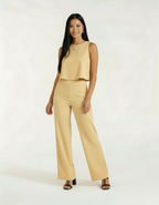 Mulher com conjunto bege amarelo claro de blusa cropped e calça wide leg com sandália preta