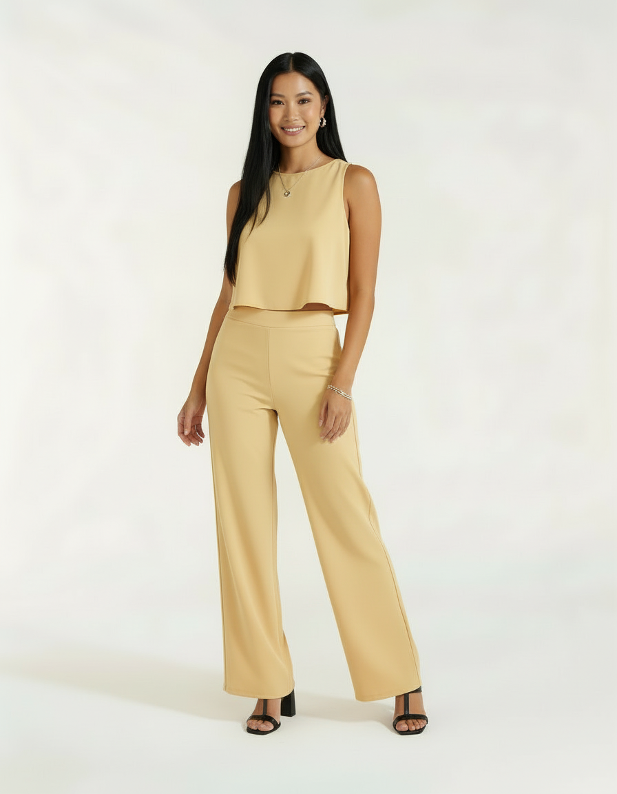 Mulher com conjunto bege amarelo claro de blusa cropped e calça wide leg com sandália preta