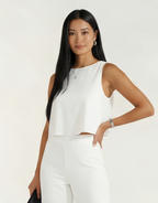 Mulher usando conjunto branco feminino elegante com blusa cropped sem mangas e calça de alfaiataria