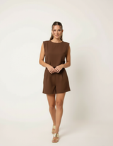 Mulher com conjunto marrom chocolate de blusa sem manga e shorts de alfaiataria com sandália dourada