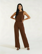 Mulher com mãos na cintura usando conjunto marrom chocolate de blusa e calça wide leg com sandália preta