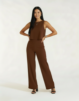 Mulher com mãos na cintura usando conjunto marrom chocolate de blusa e calça wide leg com sandália preta