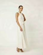 Mulher com vestido halter longo branco com cinto laço e sandália de salto bege