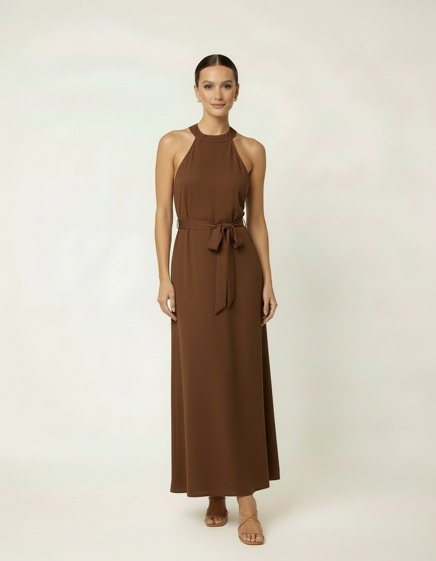 Mulher de frente com vestido halter longo marrom com cinto laço e sandália rasteira feminina