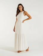 Mulher de frente com vestido longo branco off-white com saia rodada e sandália bege rasteira