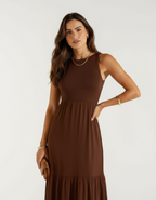 Detalhe de mulher com vestido longo marrom chocolate segurando bolsa marrom