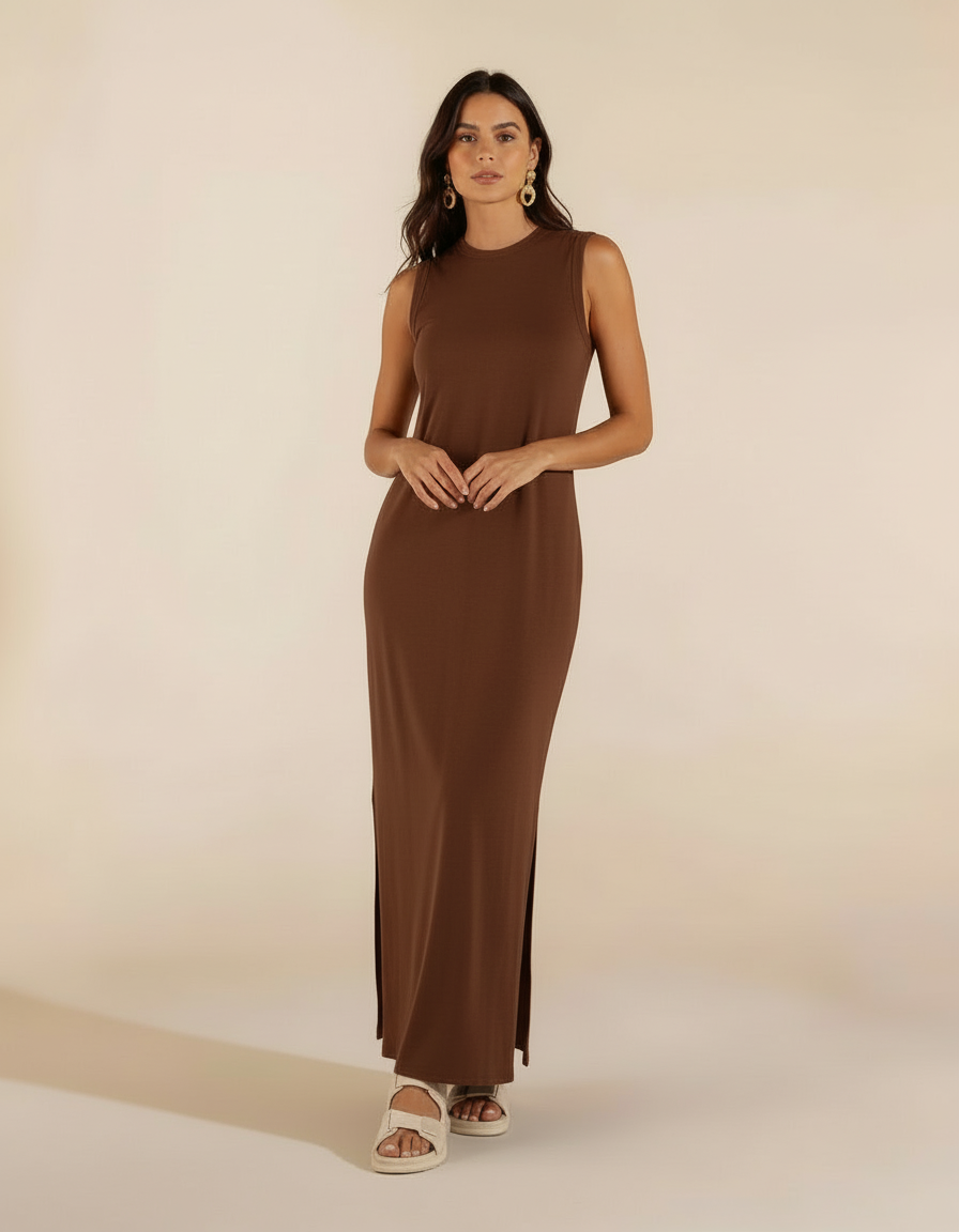 Mulher de frente com vestido longo marrom chocolate com fenda lateral e sandália branca rasteira