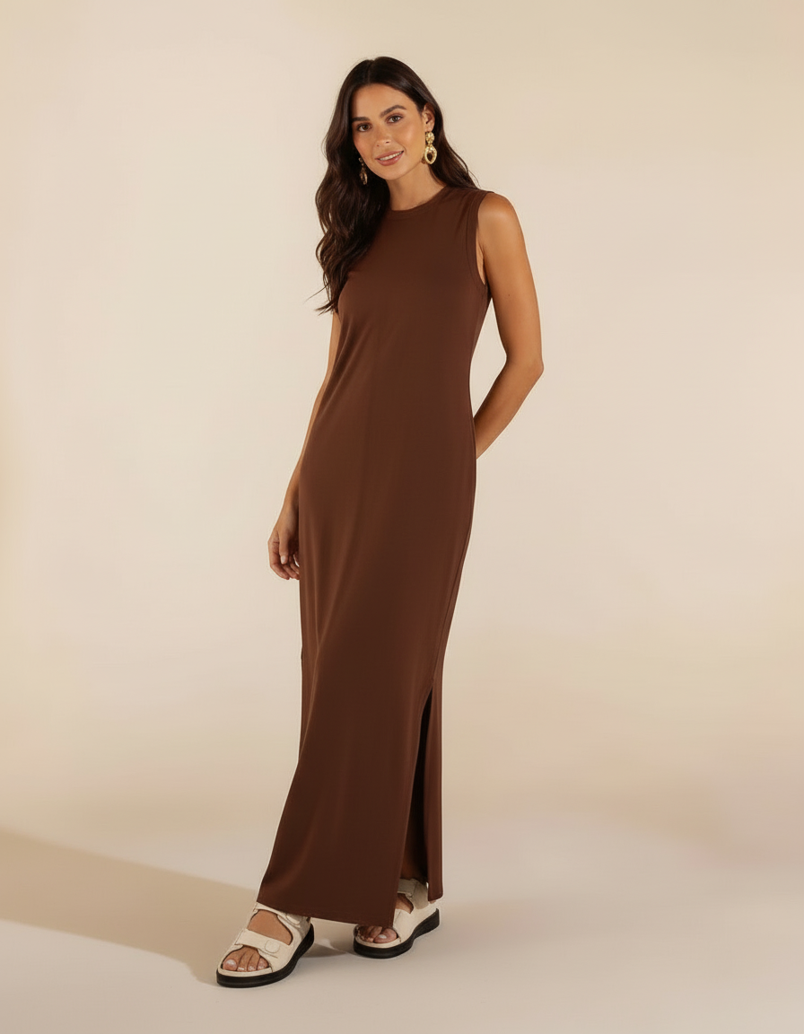 Mulher de pé com vestido longo marrom chocolate com fenda lateral e sandália branca rasteira chunky