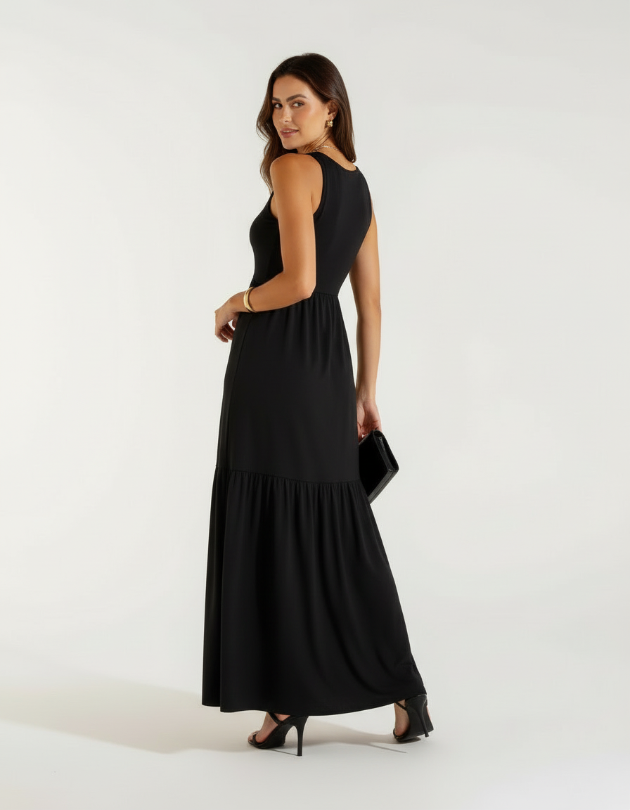 Mulher de lado com vestido longo preto com saia rodada, bolsa preta e sandália preta de salto
