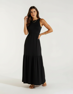 Mulher de frente com vestido longo preto com saia rodada e sandália bege rasteira
