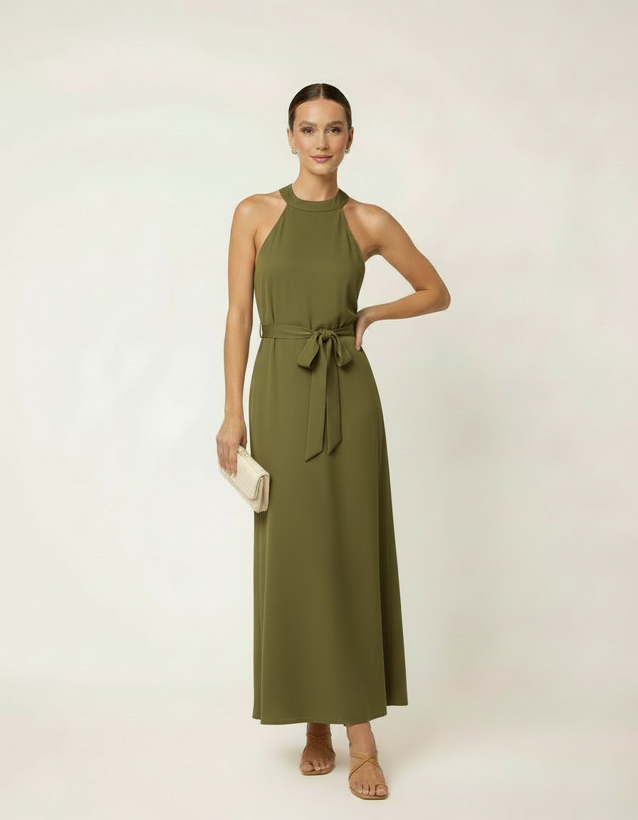 Mulher com vestido longo verde militar com cinto laço, bolsa bege clutch e sandália bege rasteira