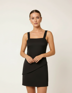 Mulher de frente com vestido curto preto de alça larga estilo bodycon com mãos à frente